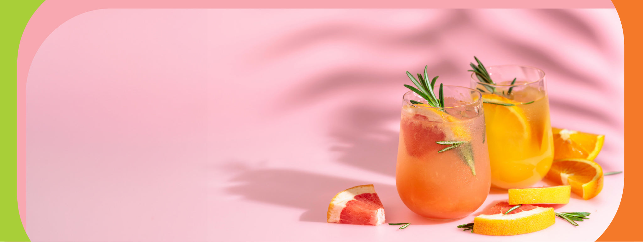 Two glasses of grapefruit beverages garnished with rosemary, on a pink background.