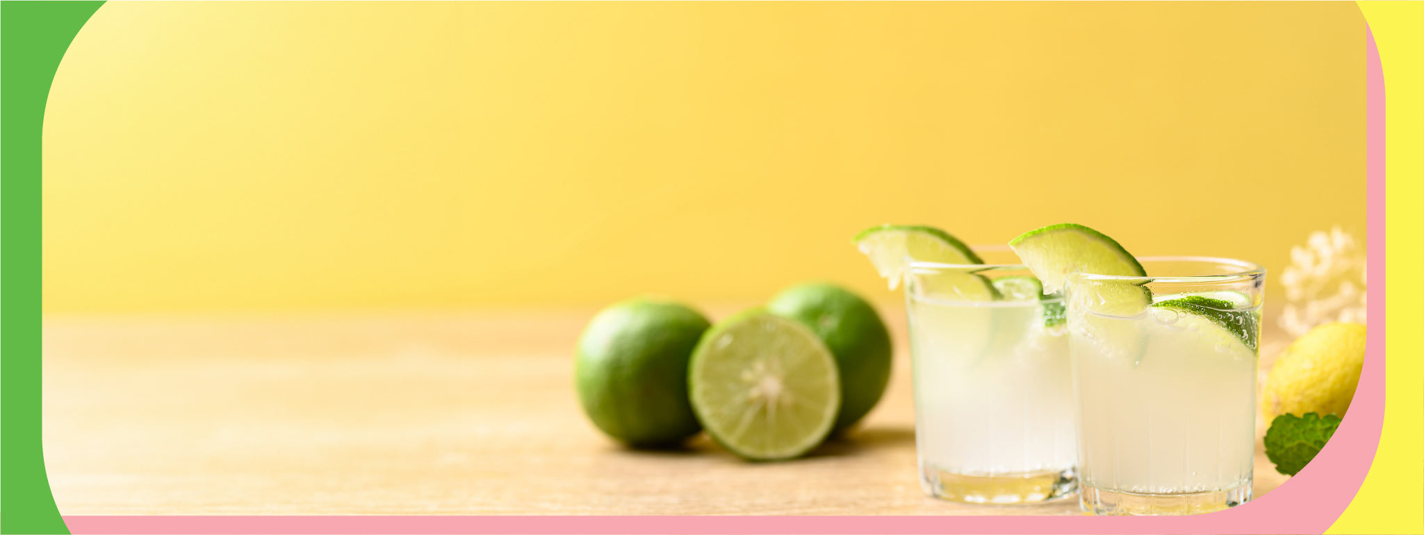 Two full cocktail glasses with lime wedge garnishes, on a yellow background.