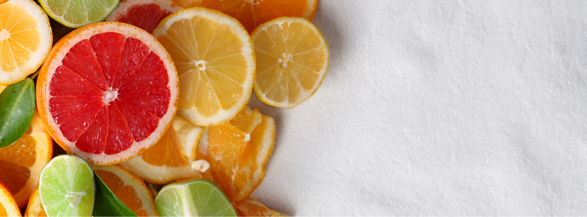 Grapefruit, lemon, lime, and orange wheels on a gray background.