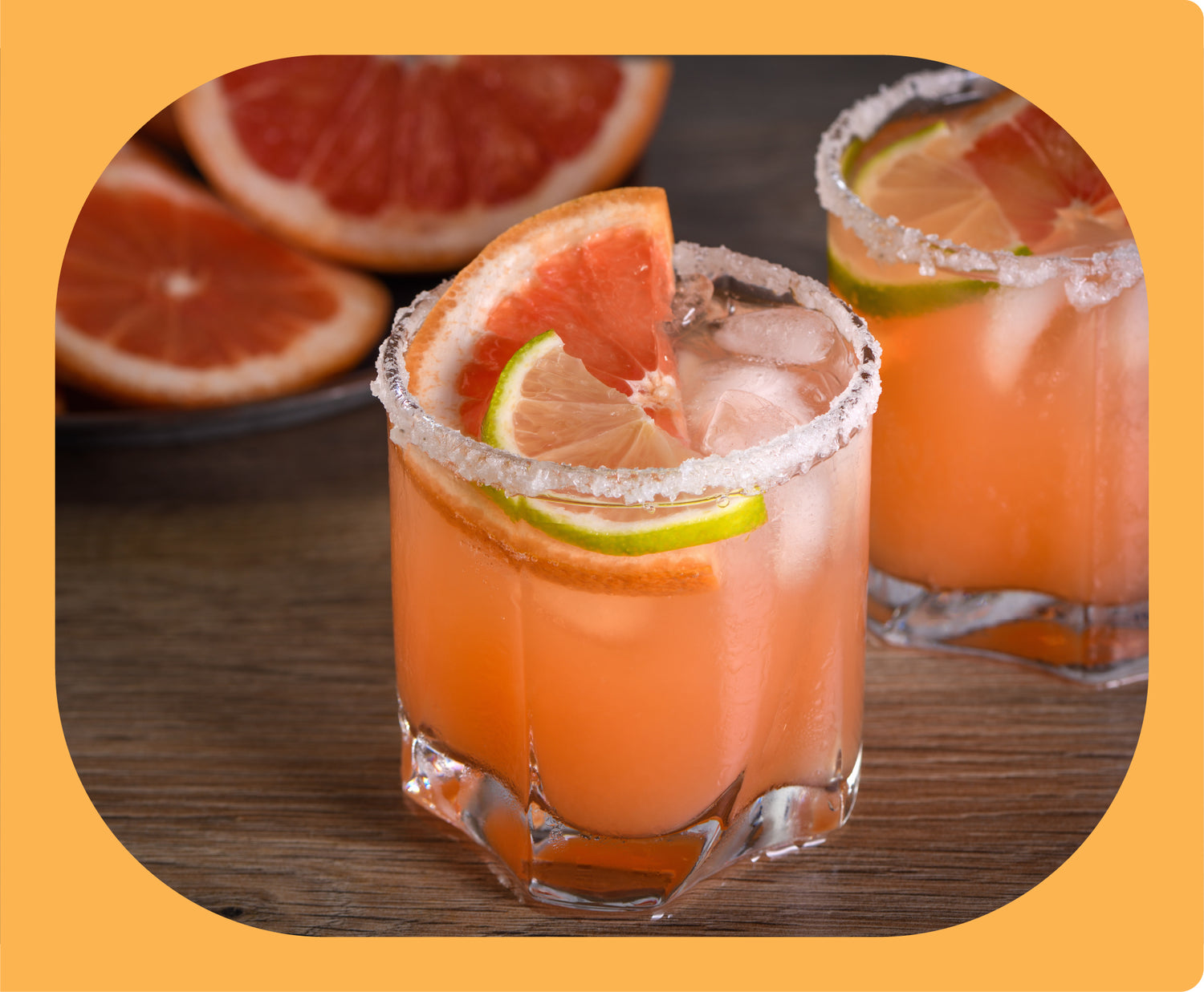 A paloma in a rocks glass, with a lime and grapefruit wedge and salt rim.